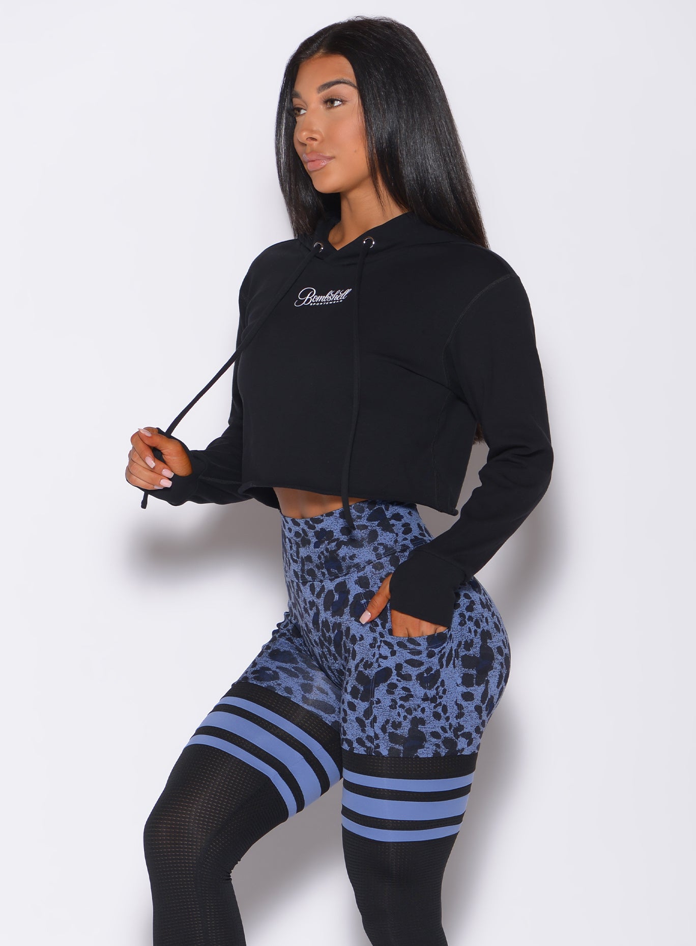 Left side profile view of a model angled left wearing our black bombshell hoodie and a cheetah print leggings