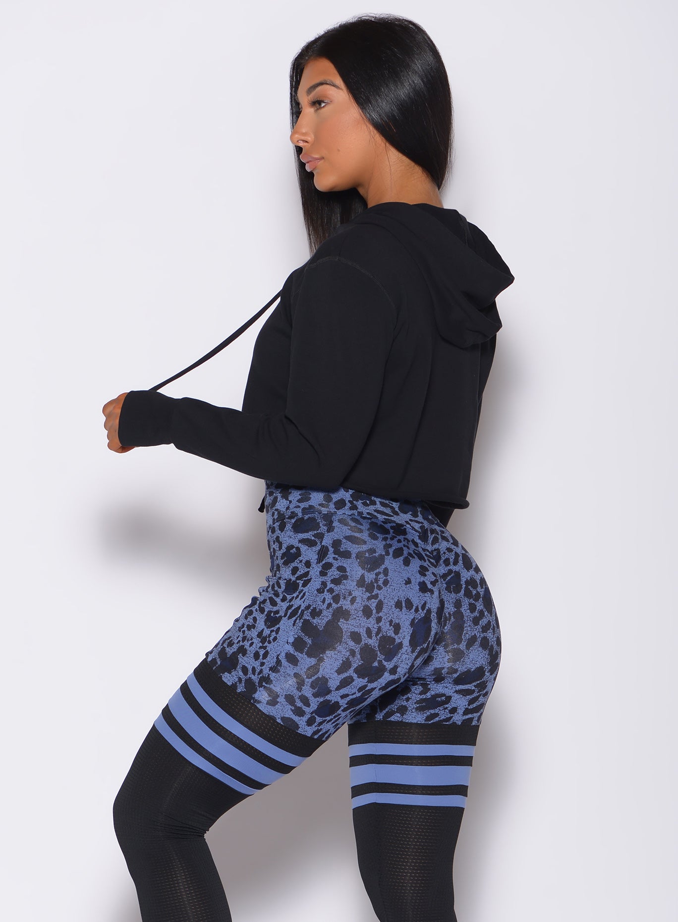 Left side profile view of a model in our black bombshell hoodie and a cheetah print leggings