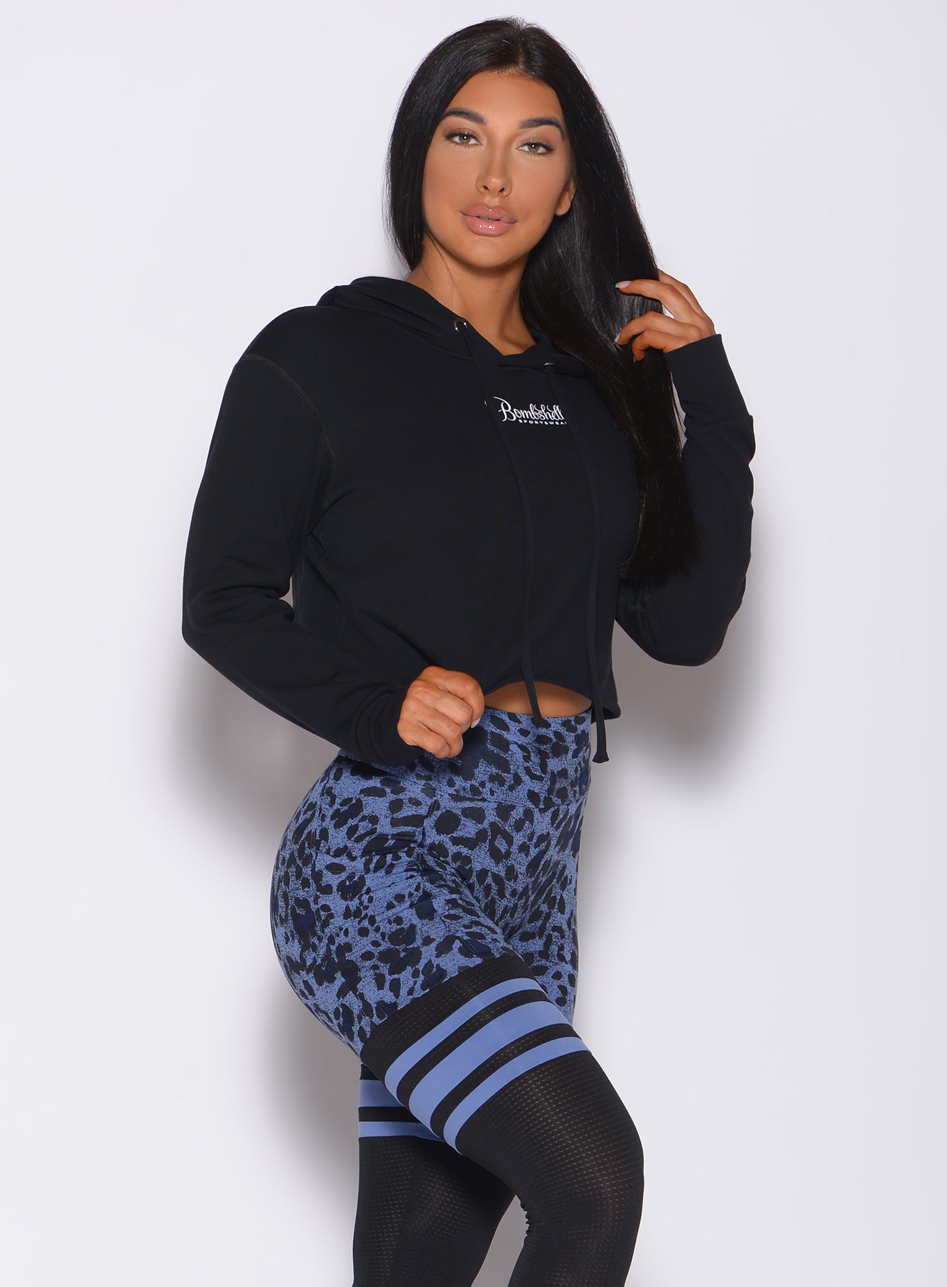 Right side profile view of a model wearing our black bombshell hoodie and a cheetah print leggings