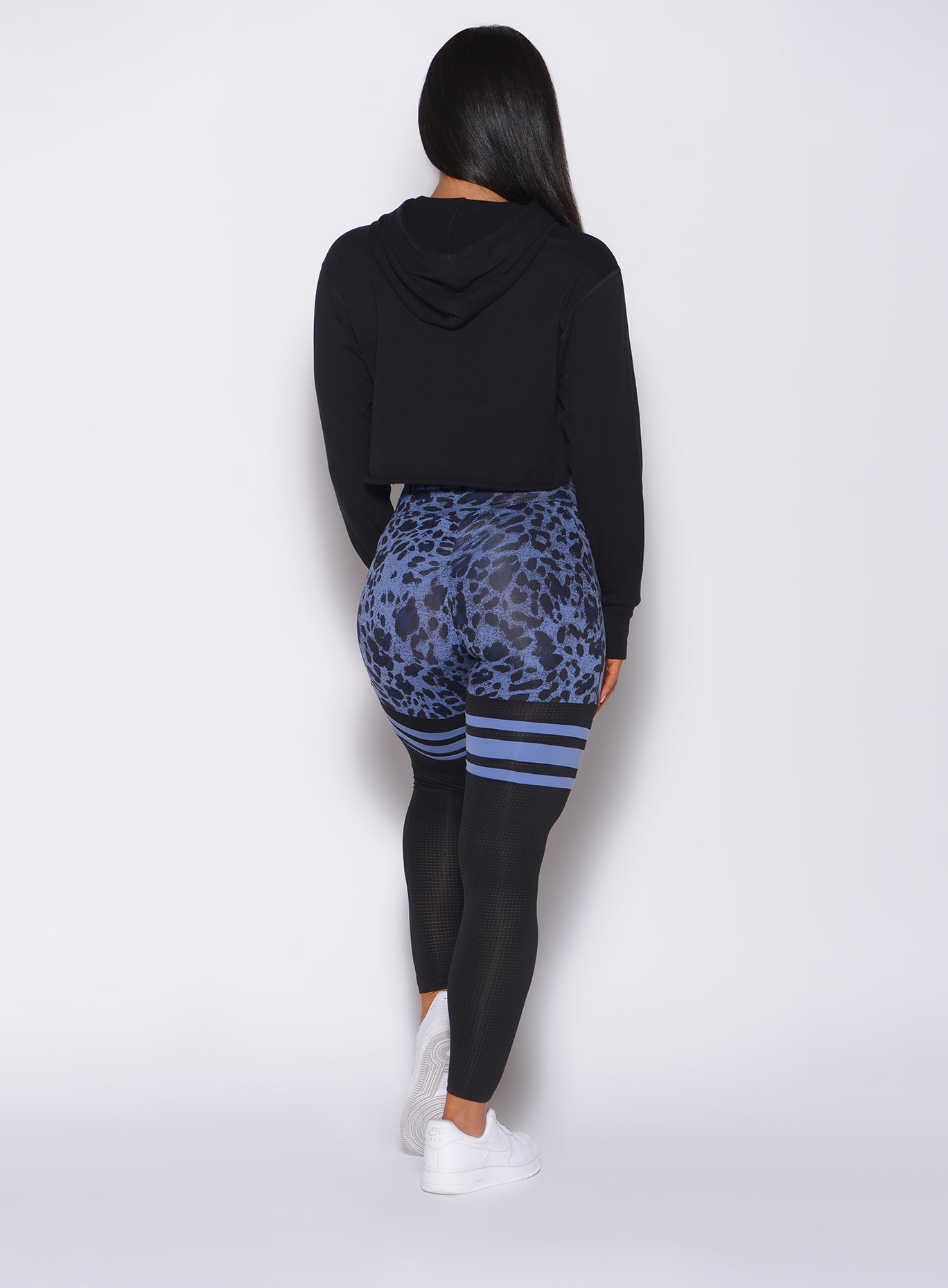 Back profile view of a model in our black bombshell hoodie and a cheetah print leggings