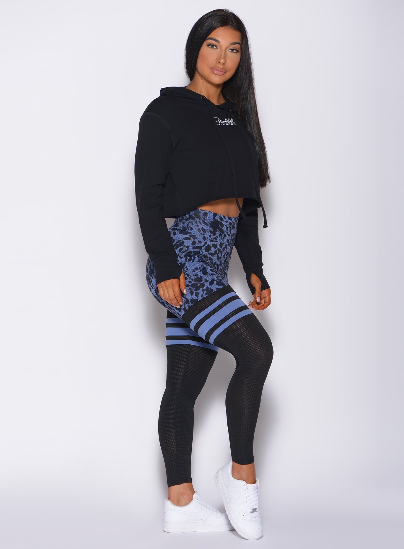 Right side profile view of a model angled right wearing our bombshell hoodie in black and a cheetah print leggings