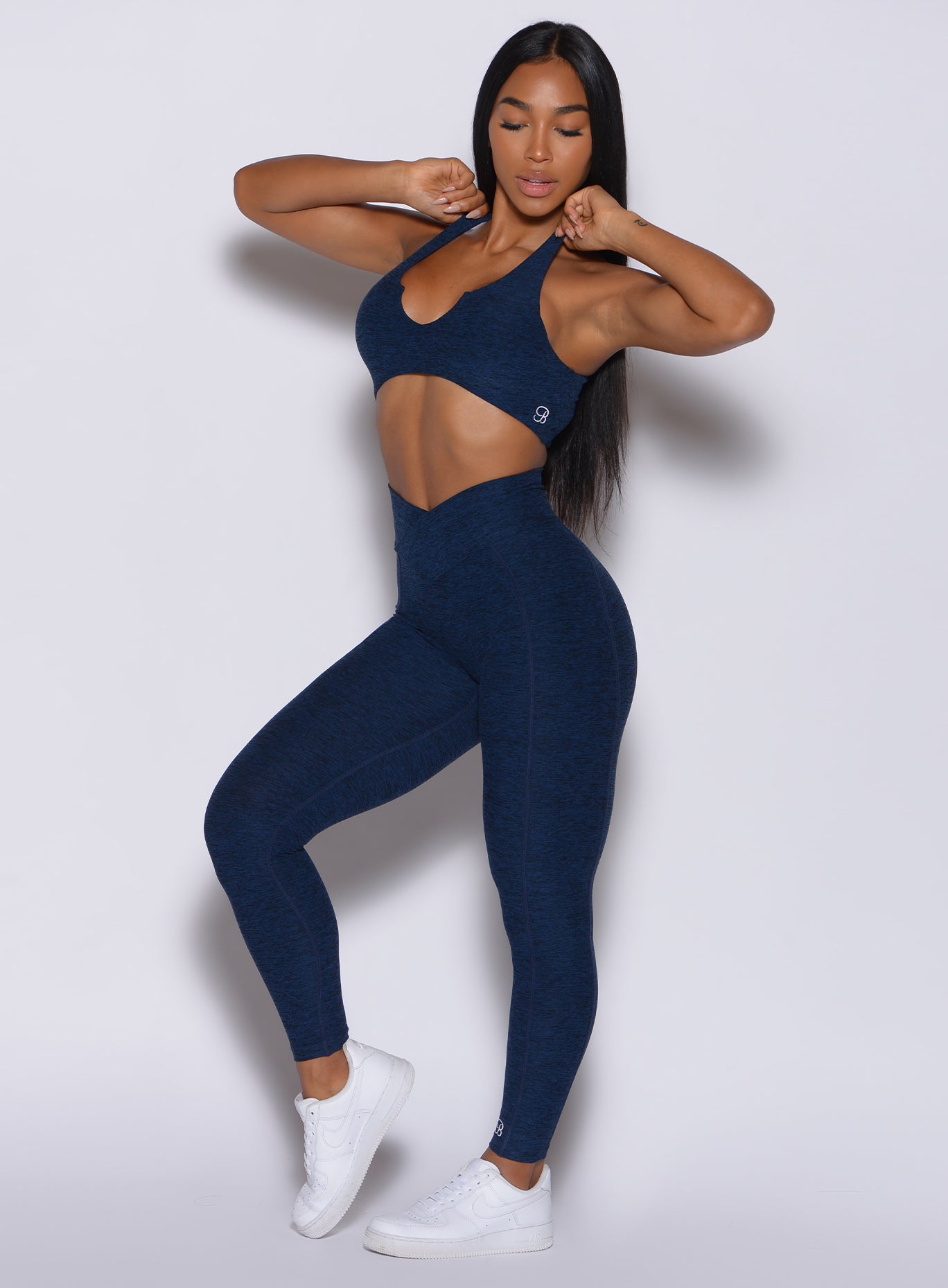 profile view of a model posing in our Brazilian Contour Leggings in sapphire blue color and a matching bra