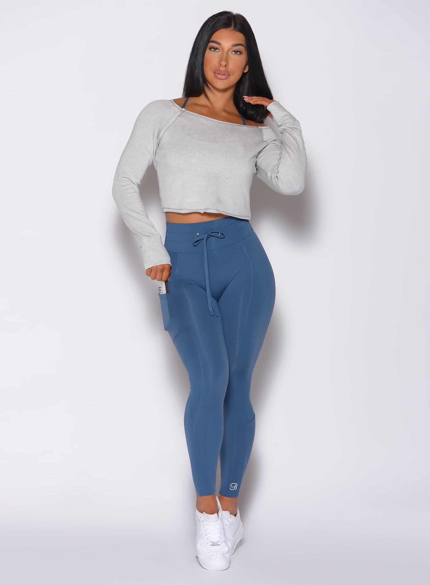 Front profile view of a model in our empower leggings in cool water color and a white hoodie