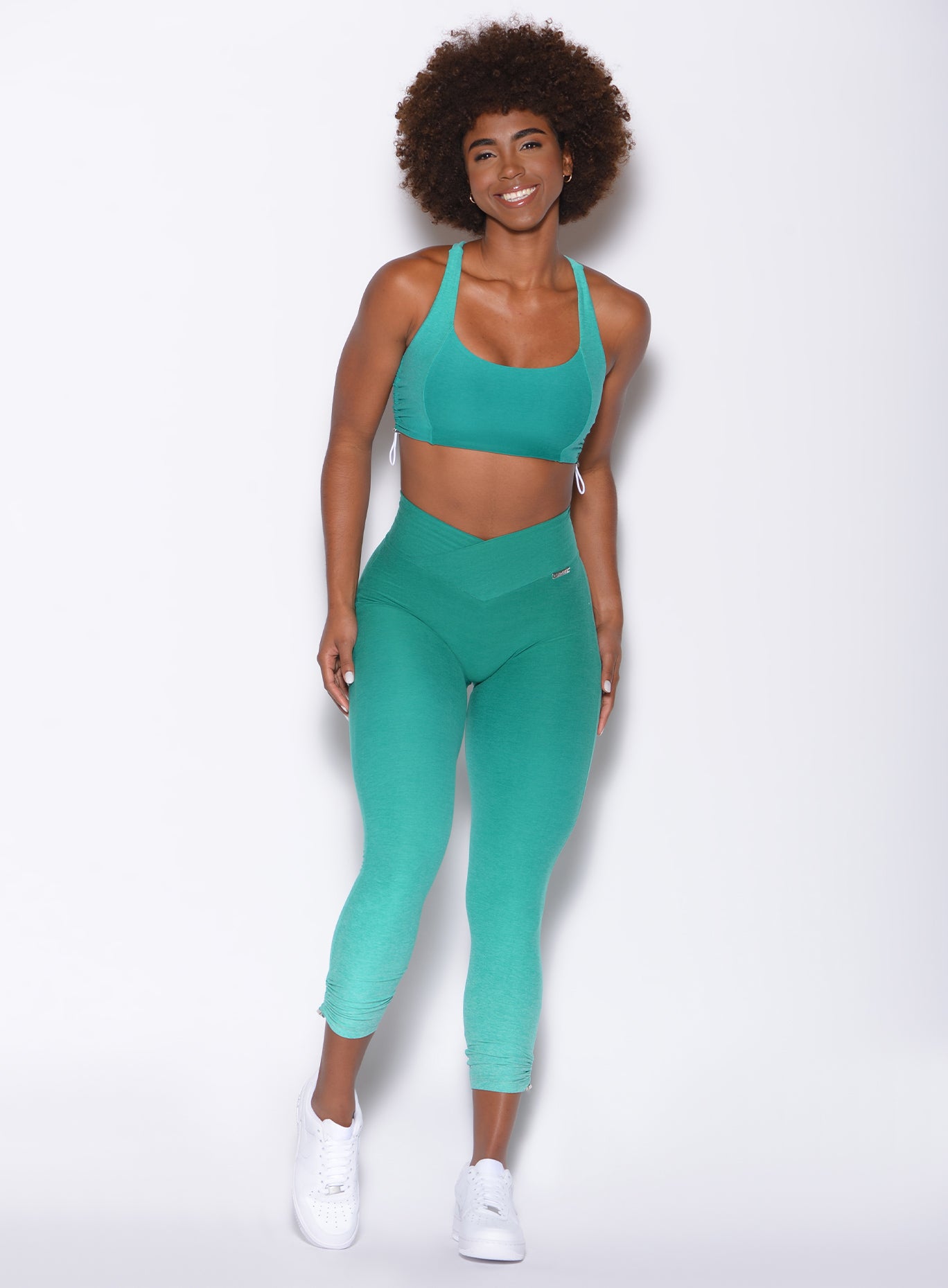 Front view of a model in our toggle leggings in Ombre Ibiza Green and a matching bra