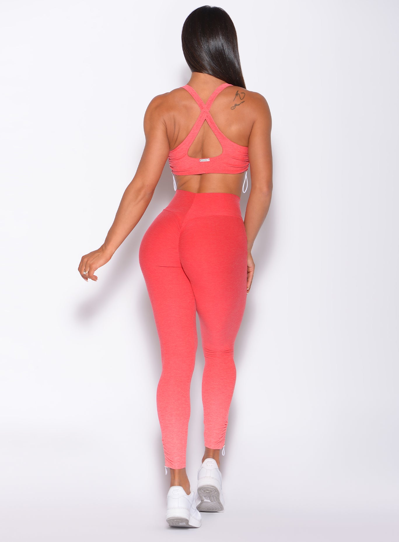 Back profile view of a model in our toggle leggings in Ombre Fiji Coral and a matching bra
