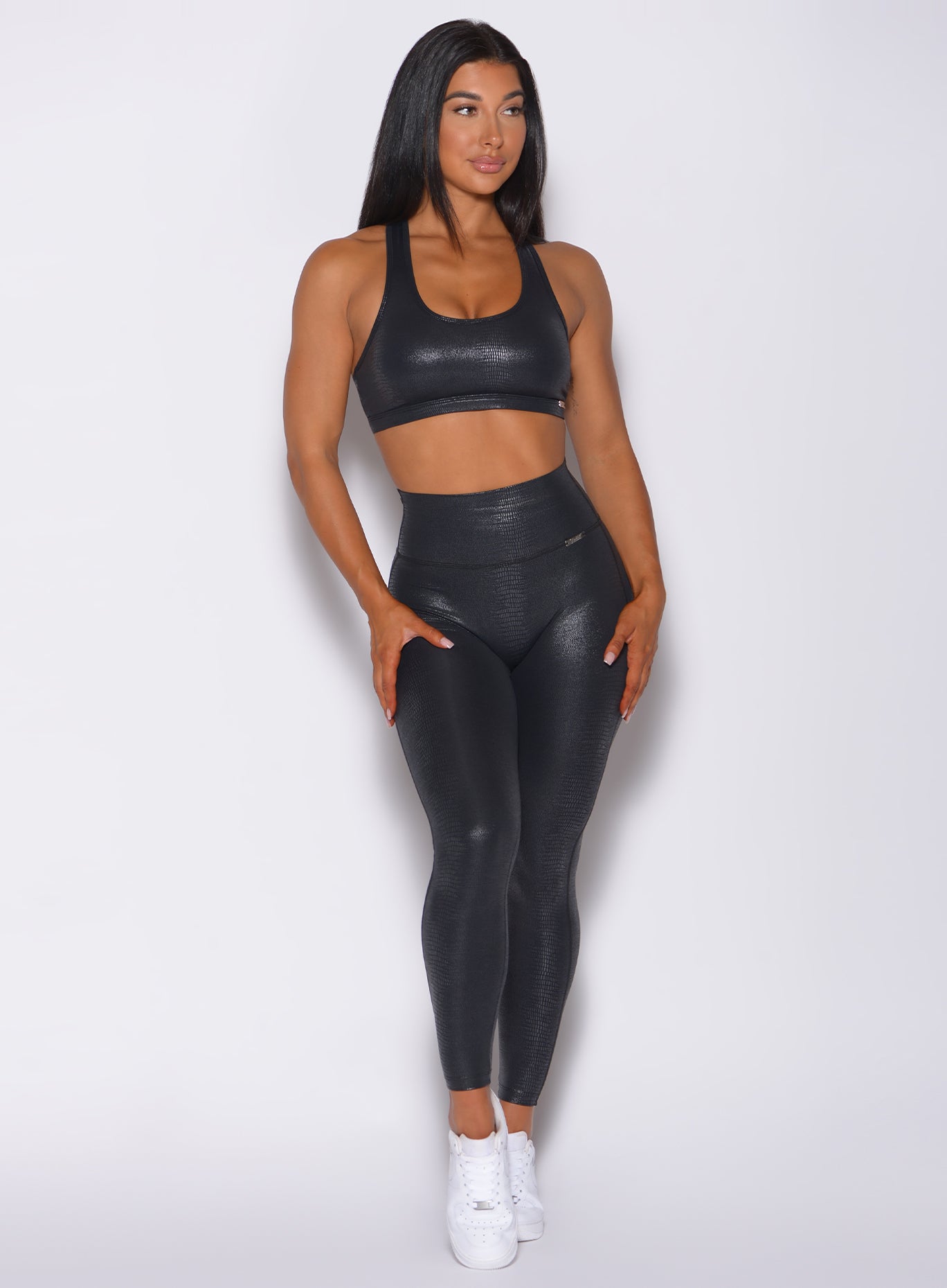 Front profile view of a model in our shine leggings in black python color and a matching bra