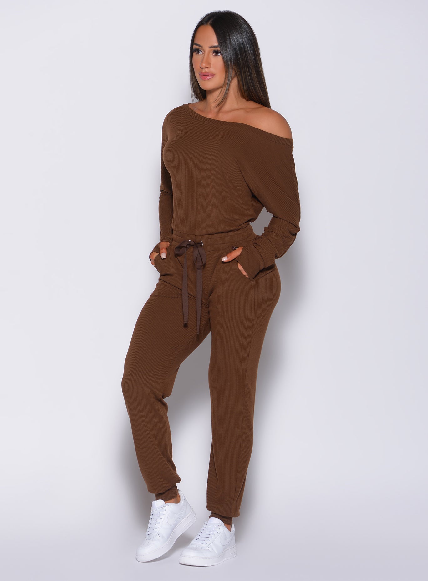 Front profile view of a model with her hands in pocket wearing our rib jumpsuit in expresso color