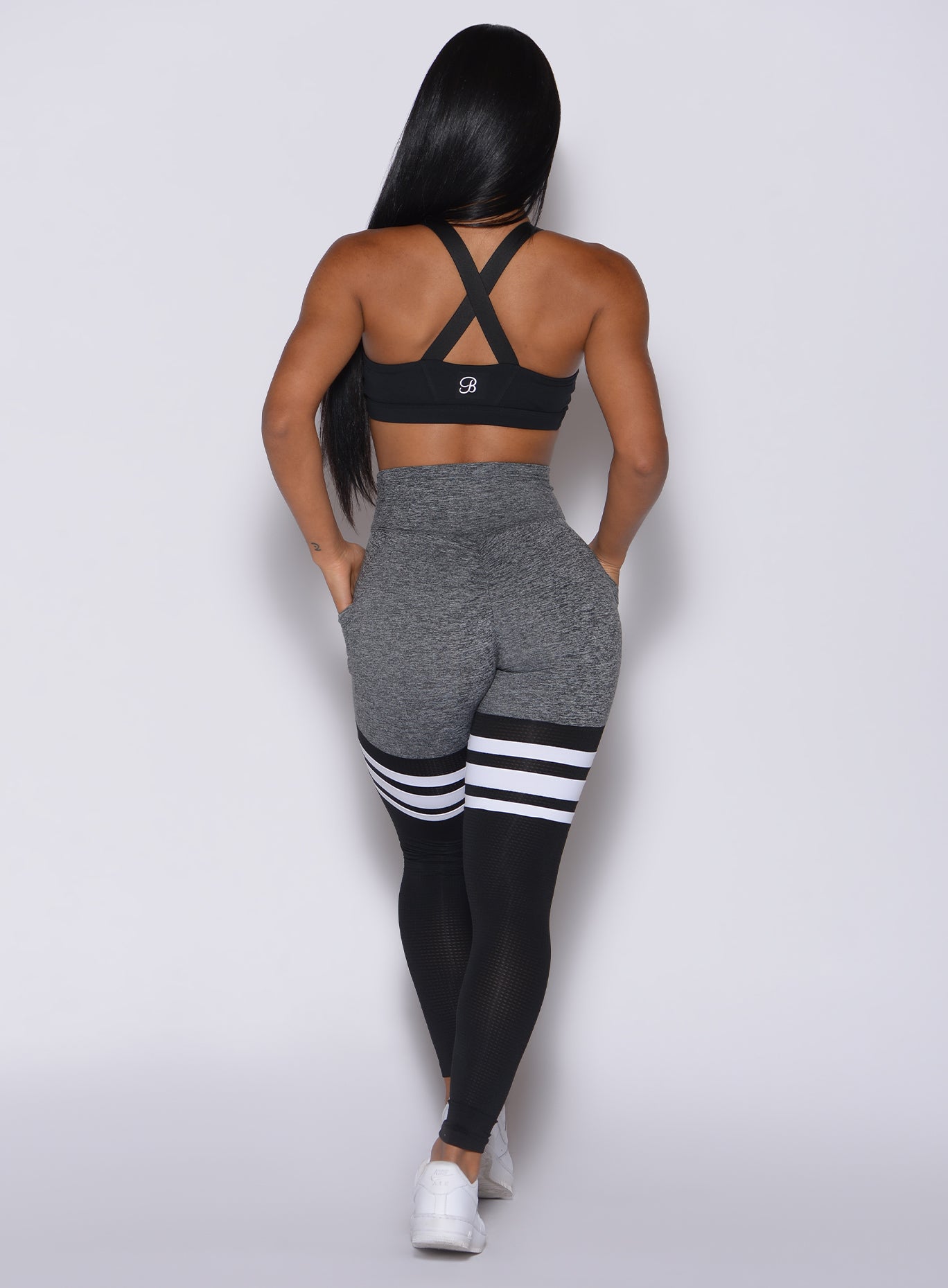 Back profile view of a model in our scrunch thigh high in gray and black with three stripes on the thighs and a matching black bra