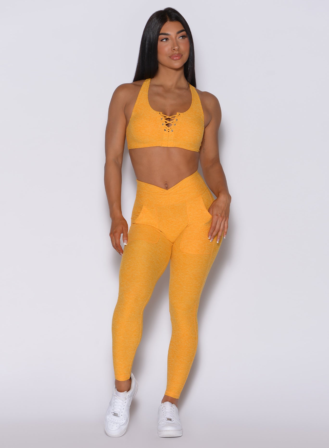 Front profile view of a model wearing our V scrunch leggings in sinkissed color and a matching bra