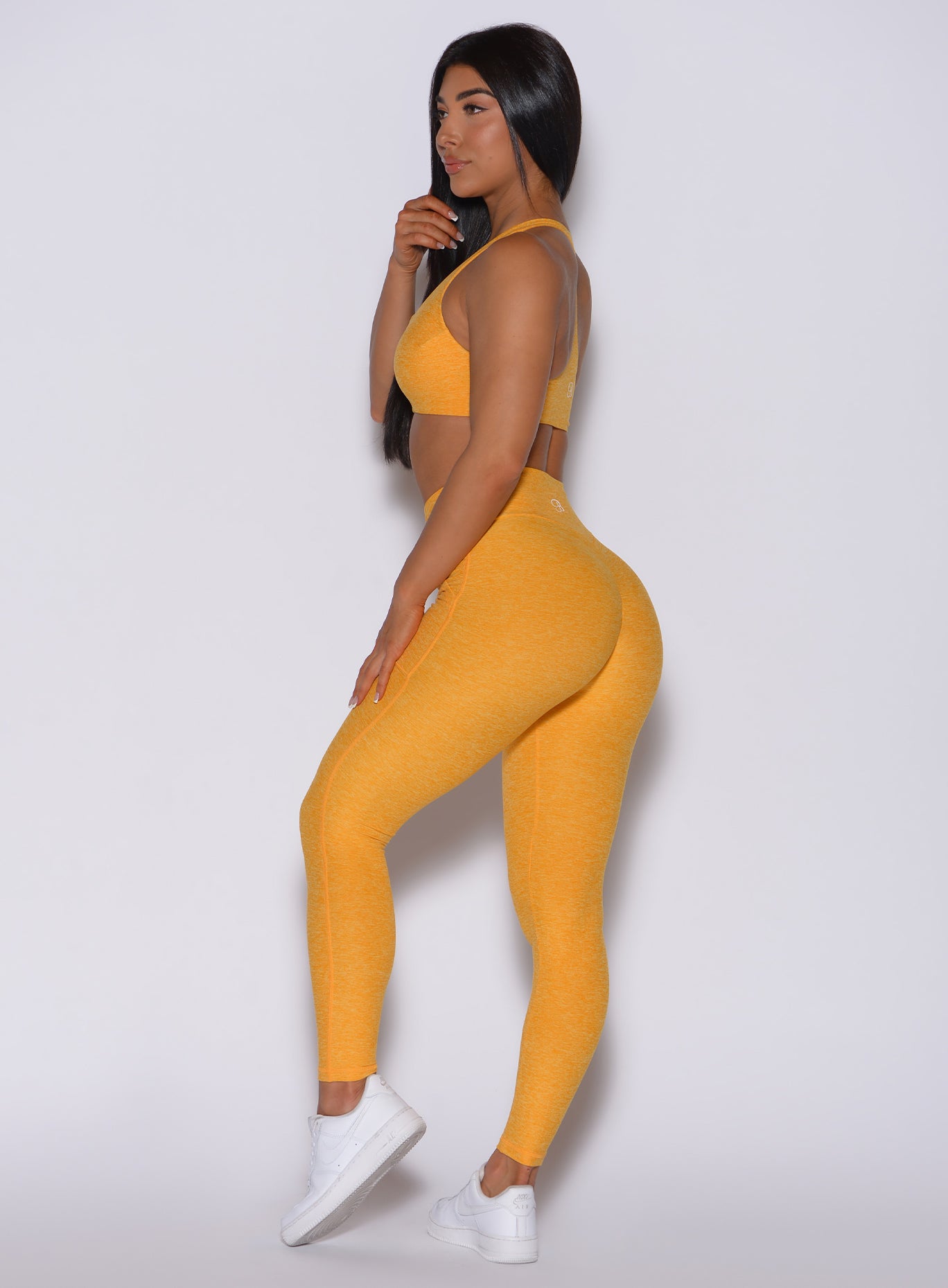 Left side profile view of a model in our V scrunch leggings in sinkissed color and a matching sports bra