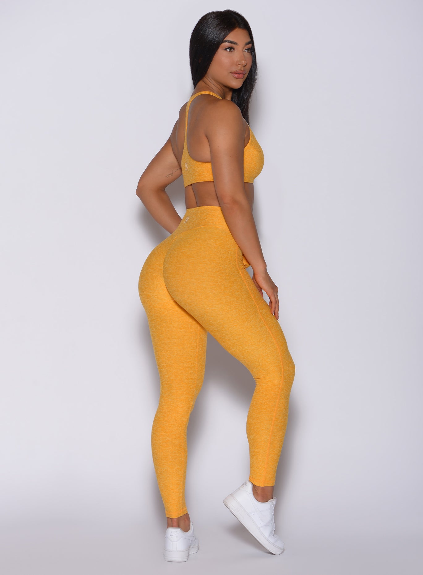 Right side profile view of a model in our V scrunch leggings in sinkissed color and a matching bra