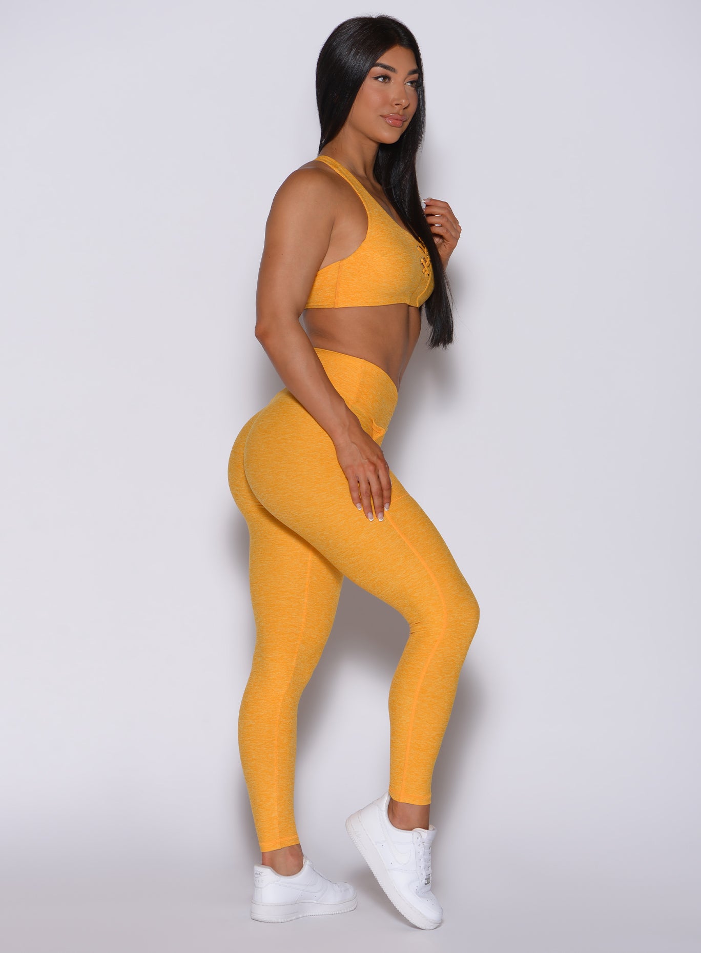 Right side profile view of a model wearing our V scrunch leggings in sinkissed color and a matching bra