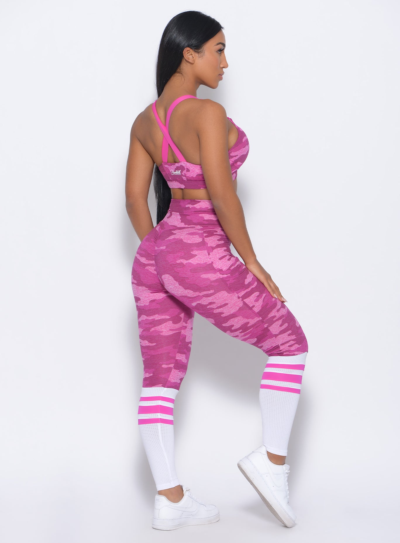 Right side view of the model facing forward in our contour sock leggings in pink camo and a matching bra