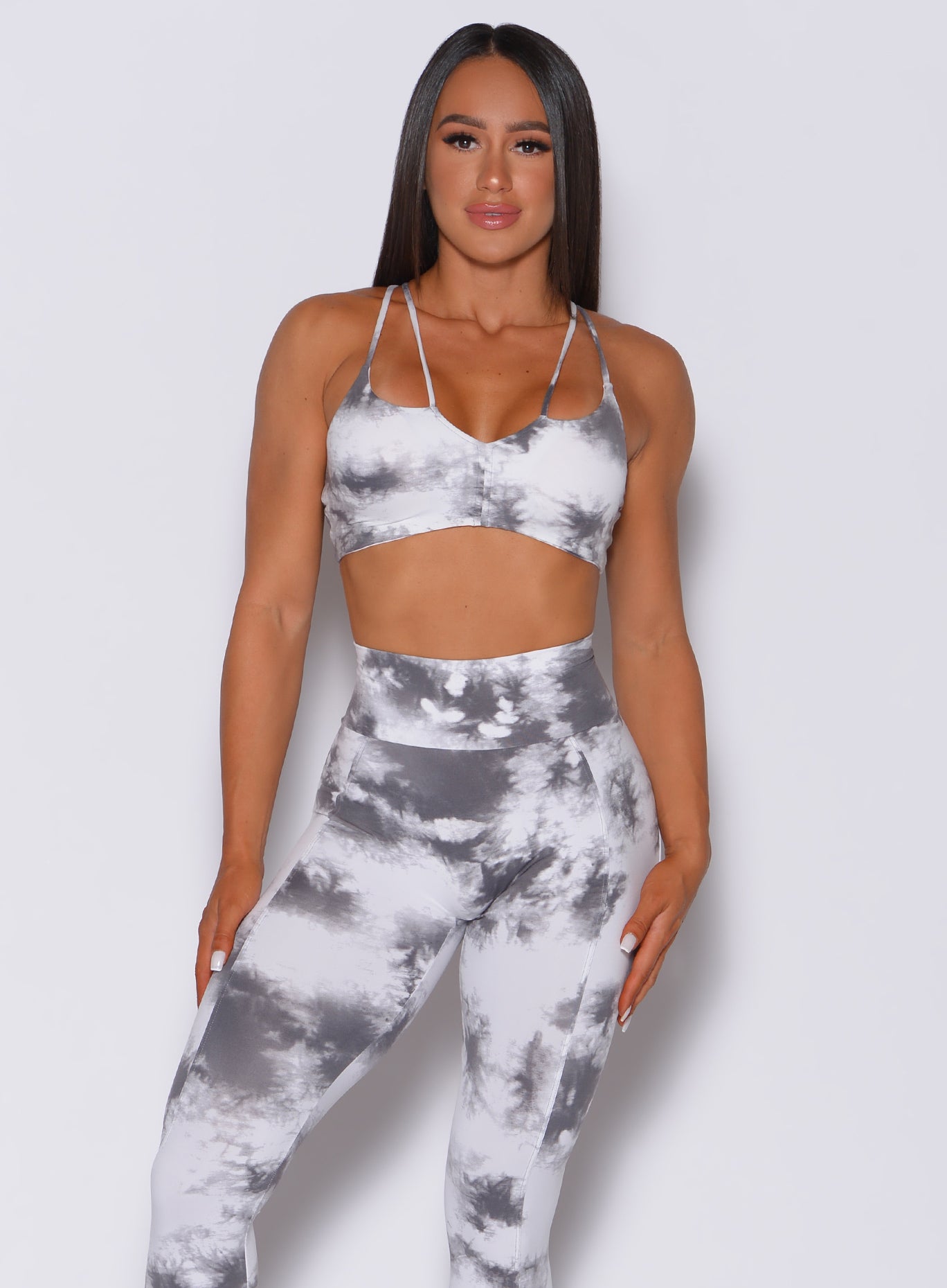 Front profile view of a model in our topnotch bra in tie dye white gray and a matching high waisted leggings