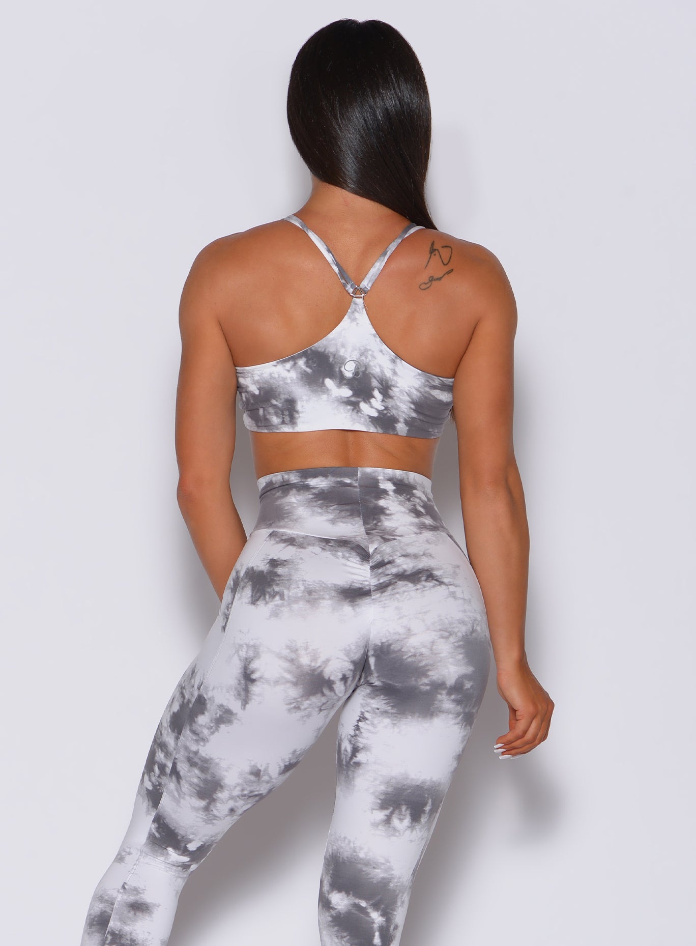 Back profile view of a model in our topnotch bra in tie dye white gray color and a matching leggings