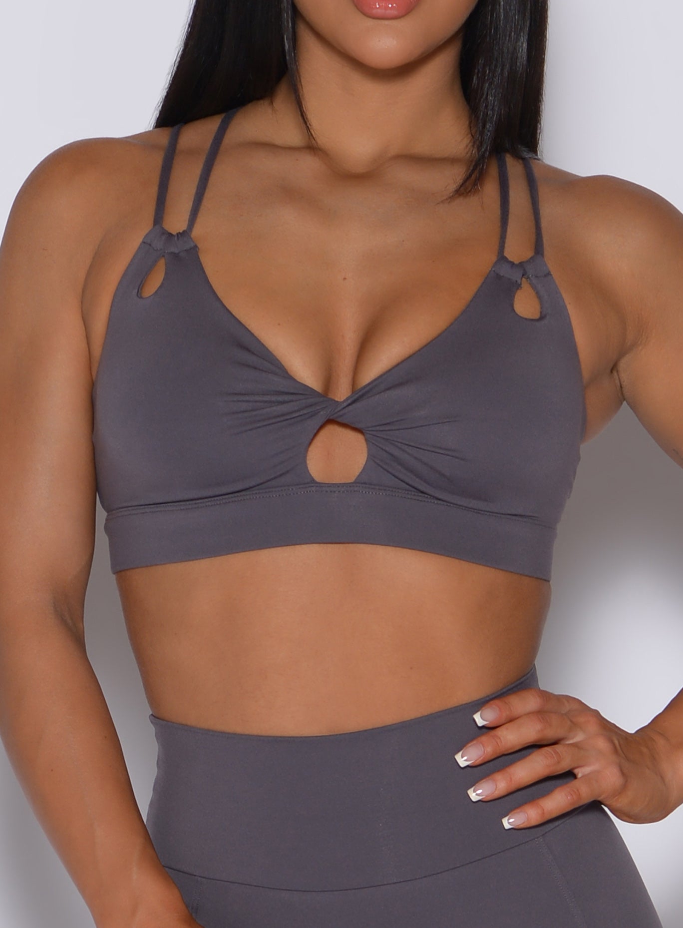 Zoomed in front profile view of a model in our twist sports bra in gray smoke